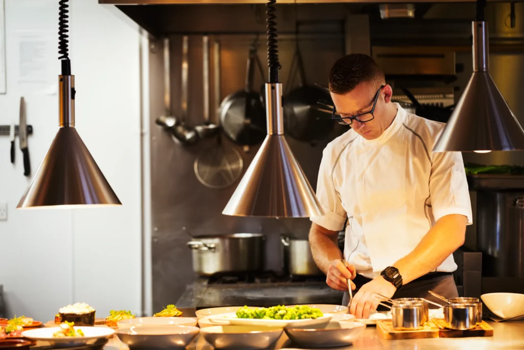 chef-standing-in-a-restaurant-kitchen-plating-foo-2026-01-09-08-40-37-utc.webp